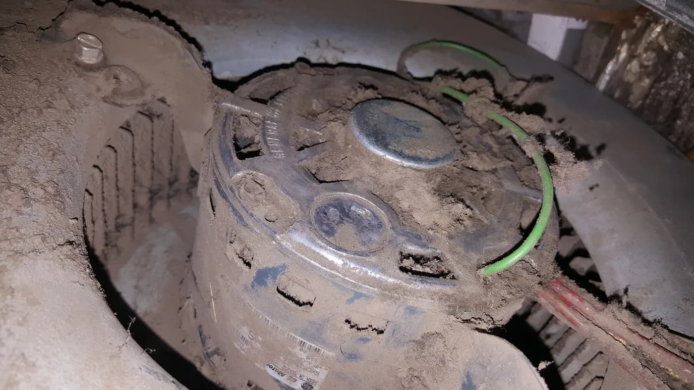 Extremely dirty blower motor covered in thick dust and debris buildup