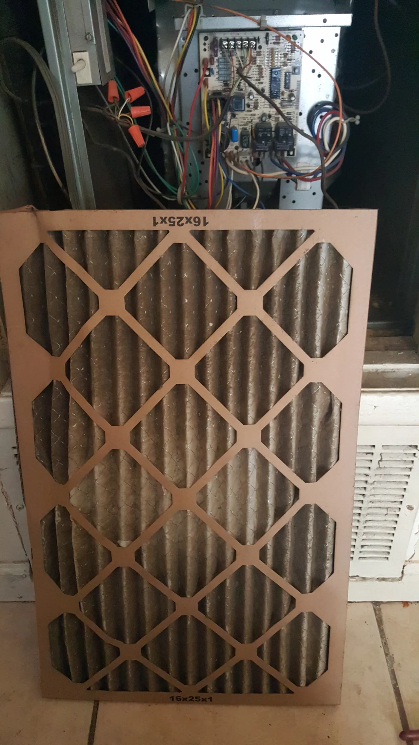 Dirty 16x25x1 air filter in furnace showing heavy dust and debris buildup