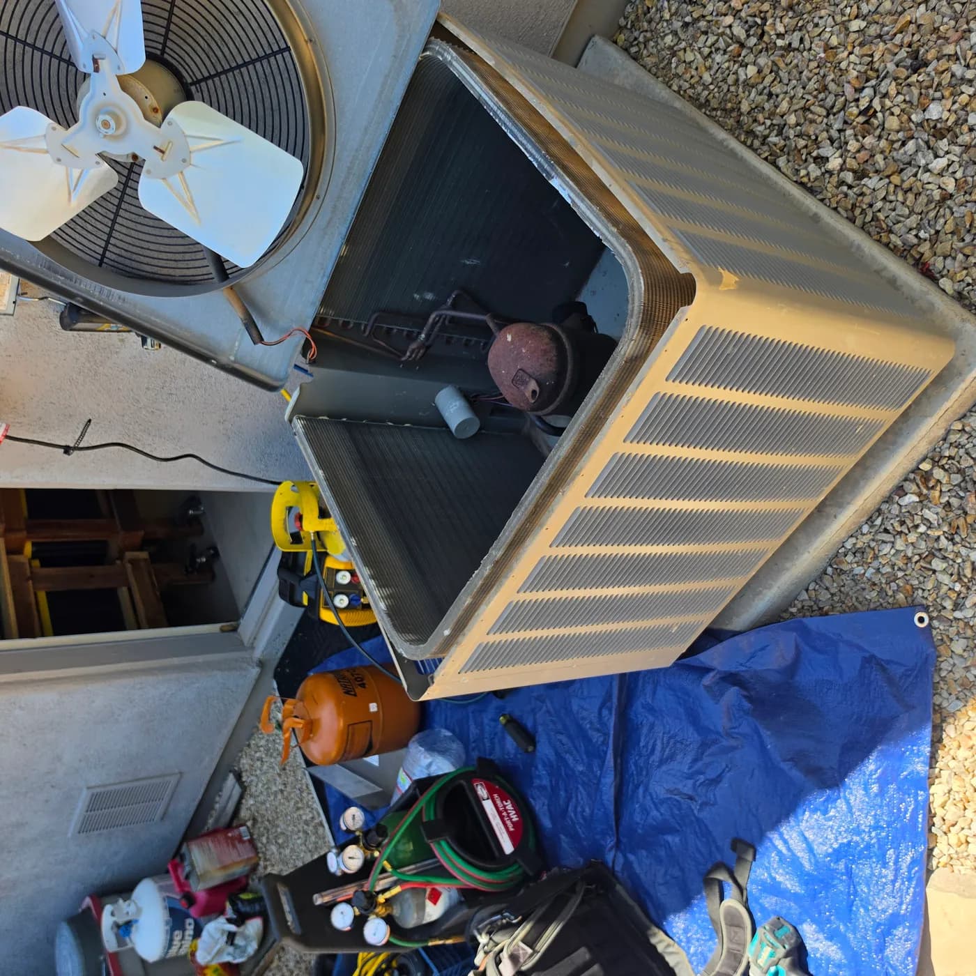 R-22 to R-407C retrofit: opened condenser cabinet with brazing torch, nitrogen and manifold gauges, and an R-407C cylinder staged for pressure testing and evacuation