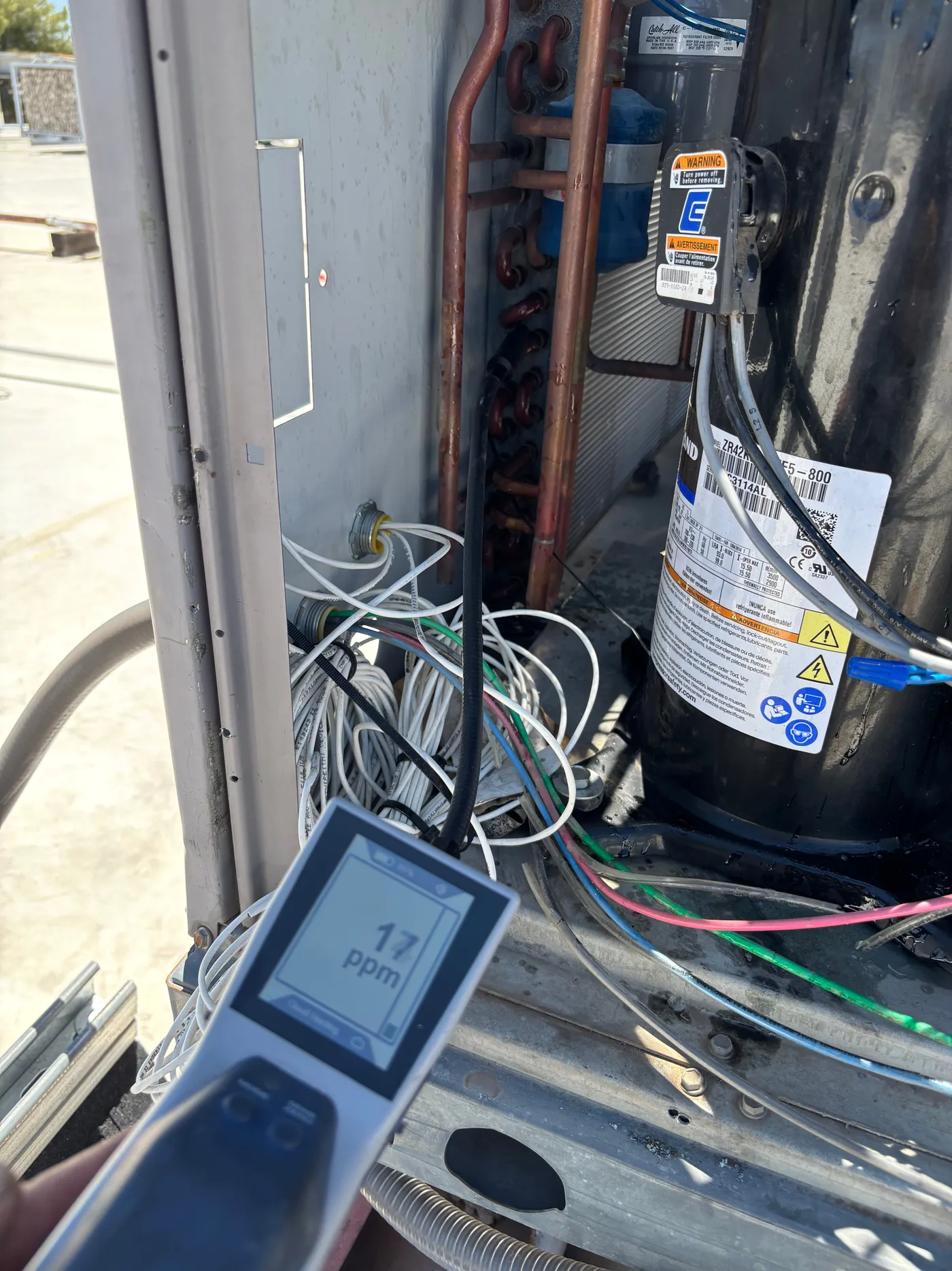 Electronic refrigerant leak detector showing 17 PPM reading during AC condenser leak diagnosis