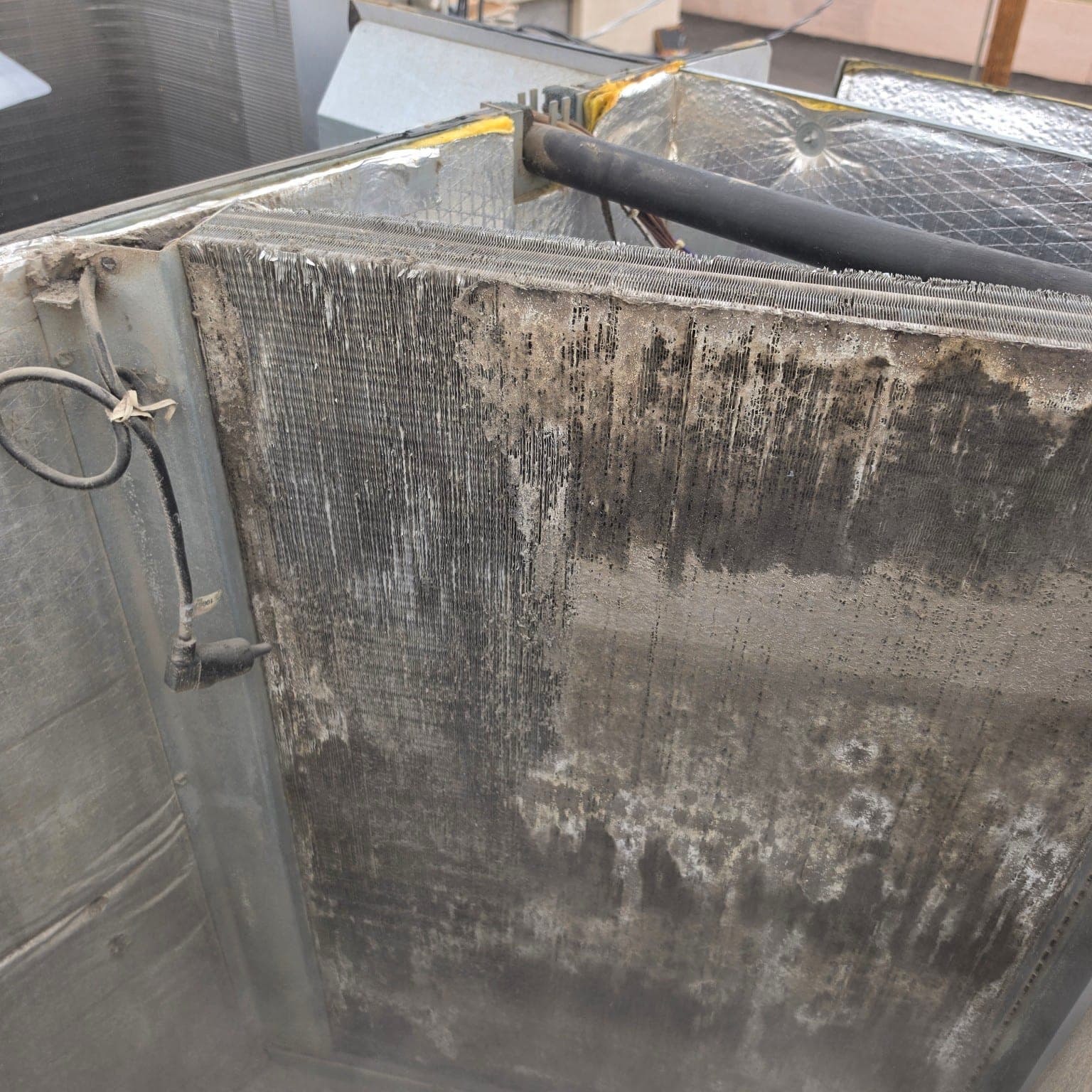 Debris buildup embedded in residential AC evaporator coil fins