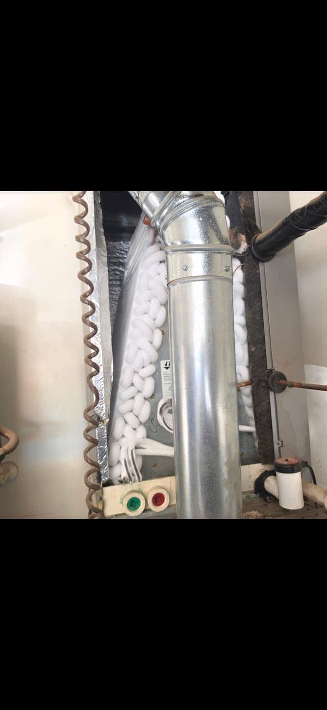 Frozen evaporator coil and refrigerant lines encased in thick ice inside a Vail air handler