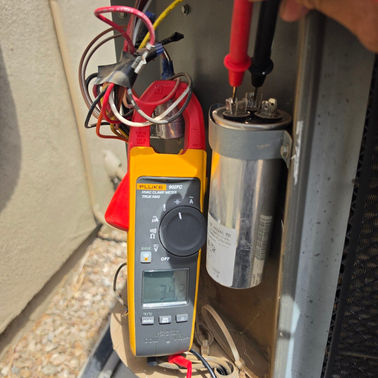 HVAC technician testing AC capacitor capacitance during preventive maintenance